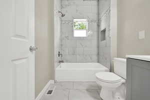 Bathroom featuring marble look tile flooring, vanity, toilet, tub / shower combination, and baseboards