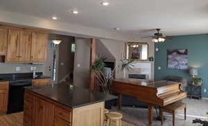 Kitchen featuring black dishwasher, a marble tiled gas fireplace, ceiling fan, recessed lighting, and a kitchen island