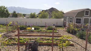 View of yard featuring a garden, fence, a mountain view, and 12'x16 shed