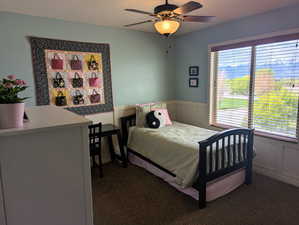 Bedroom featuring a wainscoted wall, ceiling fan, and mountain views