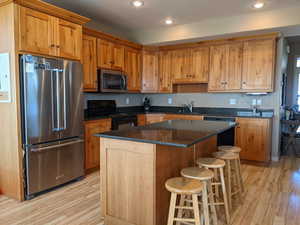 Kitchen featuring appliances with stainless steel finishes, light wood finished floors, a center island, and recessed lighting