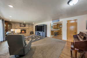 Living area featuring a textured ceiling, wood finished floors, a fireplace, baseboards, and recessed lighting