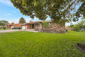 Ranch-style home with an attached garage, driveway, a chimney, a porch, and stone siding