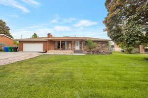 Ranch-style house with covered porch, brick siding, concrete driveway, a front yard, and a garage