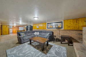 Living area featuring carpet, a textured ceiling, and wood walls