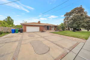 Single story home with a garage, concrete driveway, brick siding, a chimney, and a porch