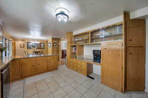 Kitchen featuring a chandelier, light tile patterned flooring, a peninsula, dishwasher, and open shelves