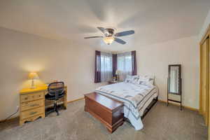 Bedroom with carpet, baseboards, ceiling fan, and a desk