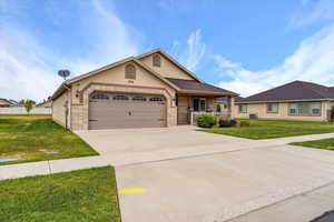 View of front of property featuring driveway, a front lawn, stucco siding, and brick siding
