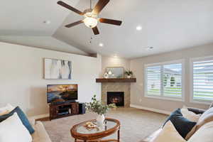 Carpeted living area featuring lofted ceiling, a tiled fireplace, baseboards, ceiling fan, and recessed lighting