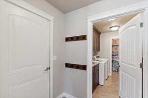 Washroom featuring cabinet space, washing machine and dryer, and light tile patterned floors