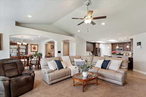 Living room featuring arched walkways, recessed lighting, a chandelier, lofted ceiling, and a ceiling fan