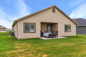 Back of house with central AC unit, a patio, a yard, and stucco siding
