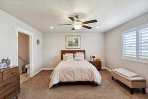 Carpeted bedroom with baseboards, a ceiling fan, recessed lighting, and ensuite bath
