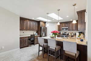 Kitchen featuring stainless steel appliances, dark brown cabinets, a peninsula, a skylight, and recessed lighting