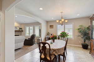 Dining room featuring plenty of natural light, arched walkways, light tile patterned flooring, recessed lighting, and a textured ceiling