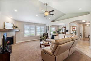 Living room with arched walkways, a ceiling fan, a chandelier, a fireplace, and recessed lighting