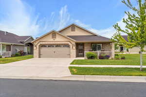 View of front facade with brick siding, an attached garage, a front lawn, driveway, and stucco siding
