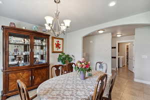 Dining room with arched walkways, recessed lighting, light tile patterned floors, baseboards, and a chandelier