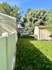 View of yard featuring fence, an outbuilding, and a shed