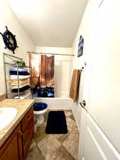 Full bath featuring vanity, a textured ceiling, shower / bath combo, and toilet