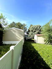 View of yard featuring a storage unit, an outdoor structure, and fence