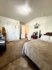 Carpeted bedroom with a textured ceiling and lofted ceiling