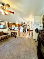 Living area featuring light floors, a ceiling fan, vaulted ceiling, and a textured ceiling