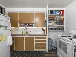 Kitchen featuring white appliances, a sink, tile countertops
