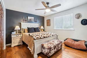 Bedroom with dark wood-style floors, a textured ceiling, baseboards, and a ceiling fan