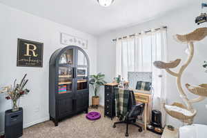 Home office with light carpet, baseboards, a textured ceiling, and arched walkways