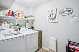 Clothes washing area with separate washer and dryer and baseboards