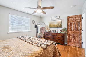 Bedroom with wood finished floors, a textured ceiling, and ceiling fan