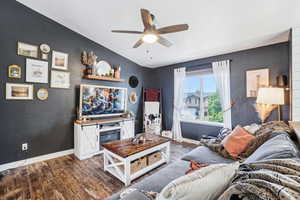 Living room with baseboards, dark wood-style flooring, a ceiling fan, and vaulted ceiling