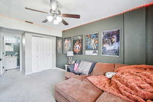 Carpeted living area featuring a ceiling fan and baseboards