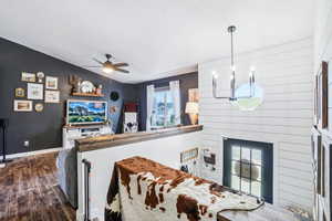 Living room featuring dark wood finished floors, a textured ceiling, ceiling fan, a chandelier, and baseboards