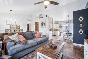 Living area with a chandelier, dark wood-style flooring, a ceiling fan, a textured ceiling, and lofted ceiling