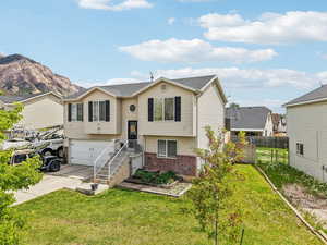 Raised ranch with brick siding, concrete driveway, a garage, and a mountain view