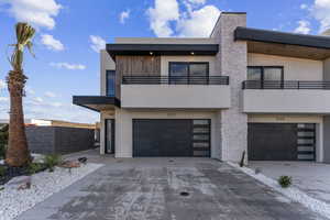 Contemporary home featuring a balcony, an attached garage, concrete driveway, stucco siding, and fence