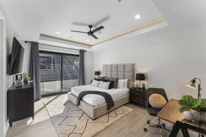 Bedroom featuring a tray ceiling, access to exterior, light wood finished floors, recessed lighting, and a ceiling fan