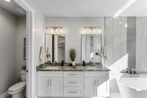 Bathroom with toilet, a freestanding bath, double vanity, and walk in shower