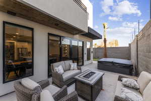 View of patio / terrace featuring a covered hot tub, an outdoor living space with a fire pit, and a fenced backyard