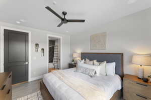 Bedroom featuring light wood finished floors, baseboards, connected bathroom, and ceiling fan