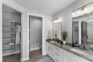 Full bathroom featuring toilet, wood finished floors, double vanity, and baseboards