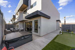 Rear view of property featuring an area to practice putting, a patio area, a balcony, a fenced backyard, and an outdoor hangout area