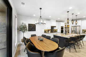 Dining room with recessed lighting, light wood-type flooring, a chandelier, and baseboards