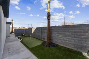 Fenced backyard featuring an area to practice putting