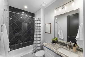 Bathroom featuring toilet, shower / bath combination with curtain, and vanity