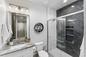 Full bath with toilet, vanity, and a stall shower