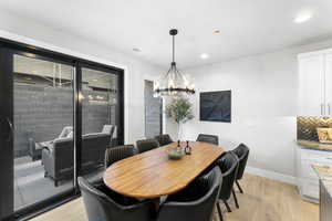 Dining area featuring light wood-type flooring, a chandelier, baseboards, and recessed lighting